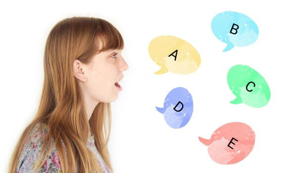 A girl speaking the alphabet in Spanish with colorful spanish letters exiting her mouth while she practices her Spanish pronunciation with a printable spanish alphabet chart
